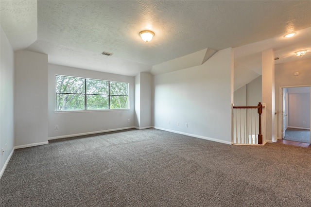 carpeted spare room with a textured ceiling and vaulted ceiling