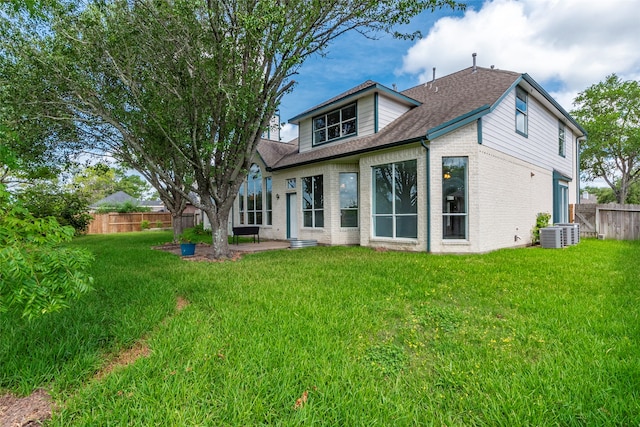 back of property with central air condition unit and a lawn