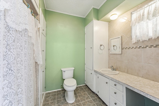 bathroom with tile patterned flooring, a textured ceiling, crown molding, vanity, and toilet