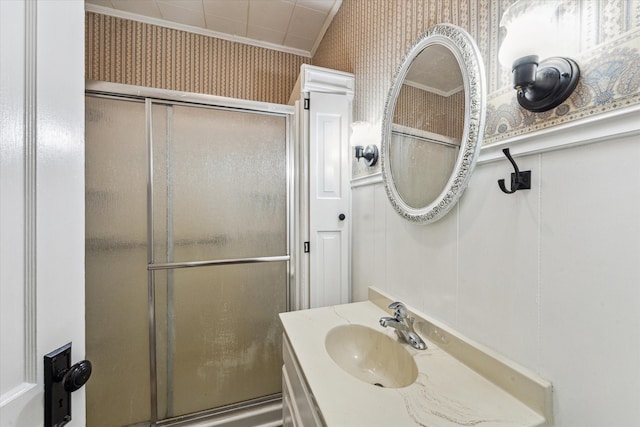 bathroom featuring ornamental molding, vanity, and an enclosed shower