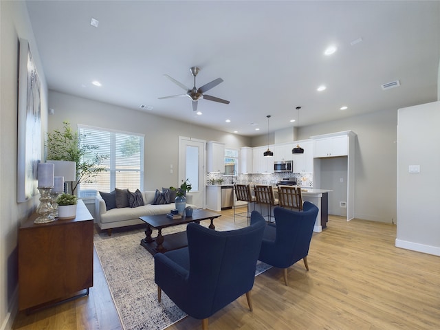 living room featuring ceiling fan, sink, and light hardwood / wood-style floors