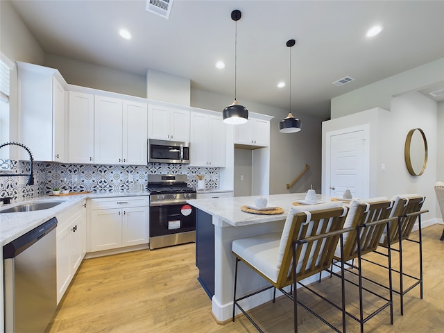 kitchen with stainless steel appliances, white cabinetry, a kitchen island, and sink