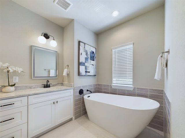 bathroom featuring a bathtub, tile walls, and vanity