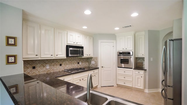 kitchen with stainless steel appliances, backsplash, kitchen peninsula, and white cabinetry