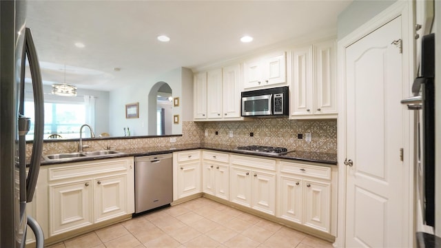 kitchen featuring dark stone counters, tasteful backsplash, light tile patterned flooring, sink, and stainless steel appliances