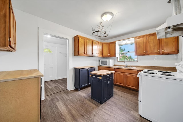 kitchen with sink, white appliances, a kitchen island, extractor fan, and hardwood / wood-style flooring