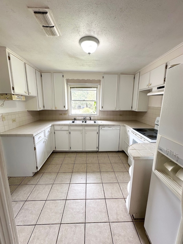 kitchen featuring light tile patterned floors, sink, white appliances, a textured ceiling, and white cabinetry