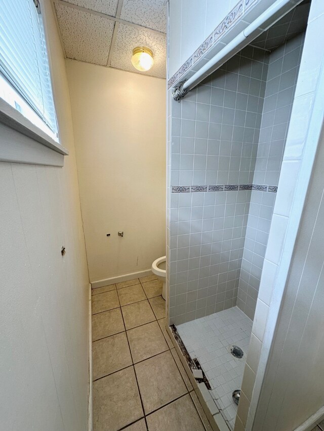 bathroom with a tile shower, toilet, and tile patterned floors