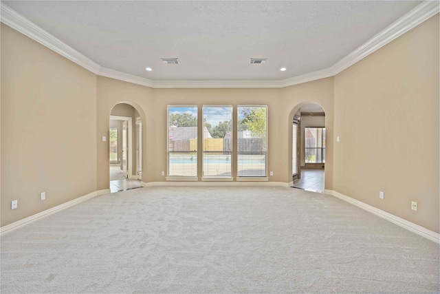 empty room featuring a textured ceiling, crown molding, and light carpet