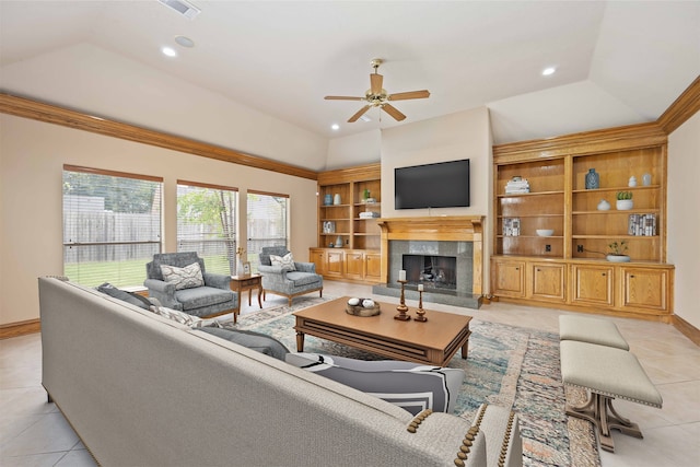 living room with a raised ceiling, a tiled fireplace, ceiling fan, and light tile patterned floors