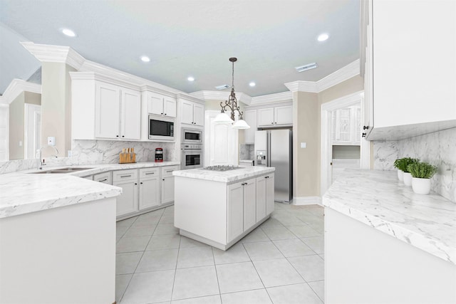 kitchen featuring appliances with stainless steel finishes, a kitchen island, sink, white cabinetry, and hanging light fixtures