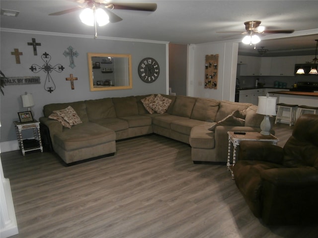 living room featuring wood-type flooring, ceiling fan with notable chandelier, and ornamental molding