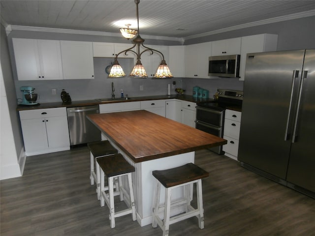 kitchen featuring pendant lighting, a breakfast bar, a center island, wood counters, and appliances with stainless steel finishes