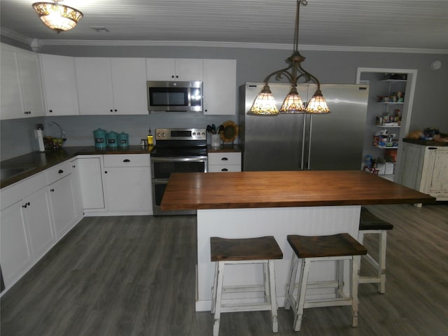 kitchen with ornamental molding, appliances with stainless steel finishes, a kitchen bar, and wooden counters