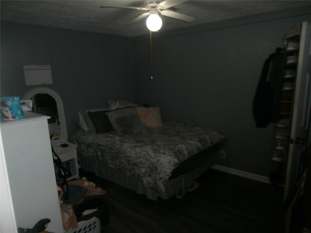 bedroom with a textured ceiling, ceiling fan, and dark hardwood / wood-style flooring