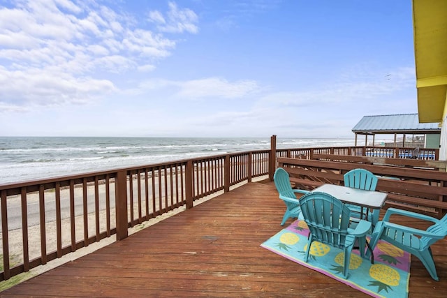 deck featuring a gazebo, a water view, and a beach view