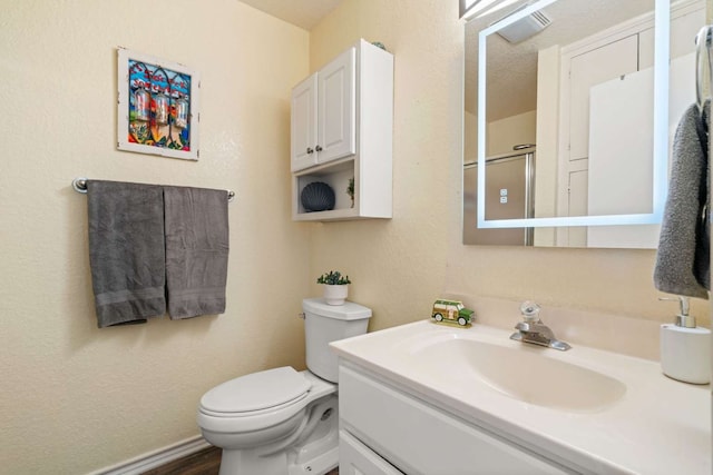 bathroom with vanity, a textured ceiling, wood-type flooring, and toilet