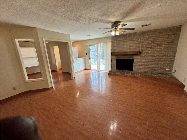 unfurnished living room featuring a textured ceiling, ceiling fan, and a brick fireplace