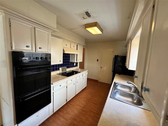 kitchen featuring decorative backsplash, white cabinets, dark hardwood / wood-style flooring, black appliances, and sink