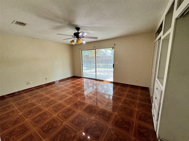 unfurnished room with ceiling fan and a textured ceiling