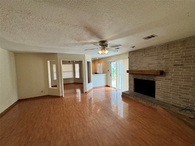 unfurnished living room featuring ceiling fan, a textured ceiling, and a brick fireplace