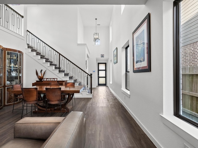 foyer entrance featuring dark wood-type flooring, an inviting chandelier, and a high ceiling