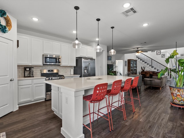 kitchen featuring dark hardwood / wood-style flooring, a kitchen island, white cabinets, and stainless steel appliances