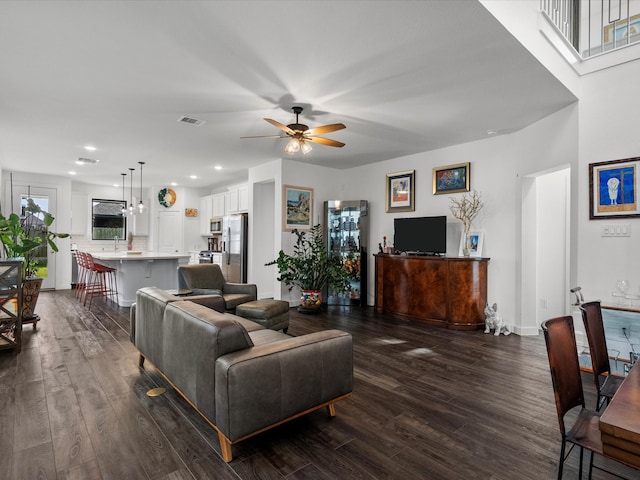 living room featuring dark wood-type flooring and ceiling fan