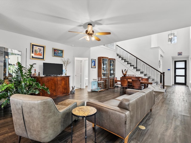 living room with ceiling fan with notable chandelier and dark hardwood / wood-style floors