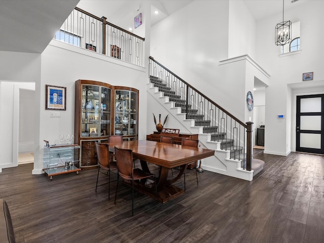 dining room with an inviting chandelier, dark hardwood / wood-style floors, and a towering ceiling