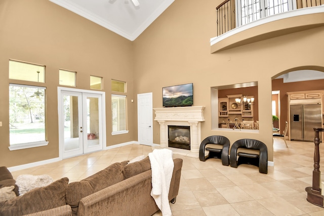 tiled living room with ornamental molding, a high ceiling, a notable chandelier, and french doors