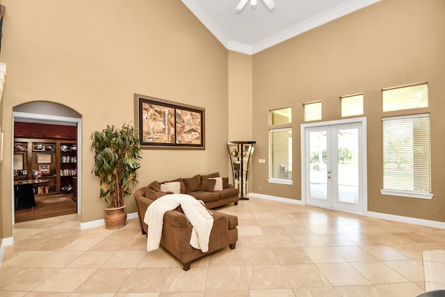 tiled living room with french doors, crown molding, a towering ceiling, and ceiling fan