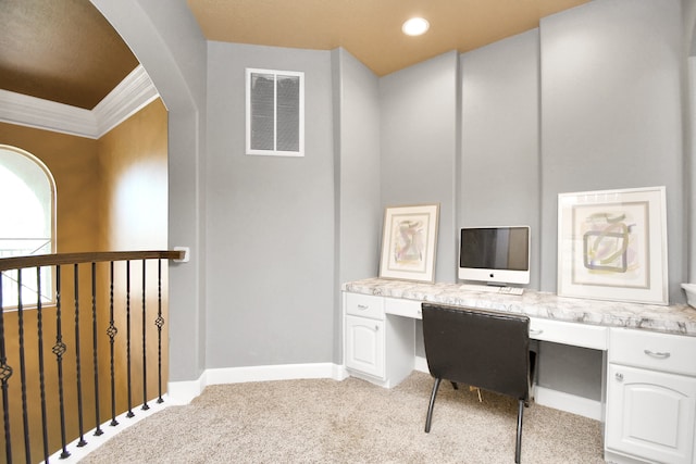 carpeted office space with built in desk and crown molding