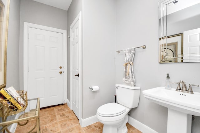 15 Bees Creek Ct, Missouri City, TX 77459 - bathroom featuring baseboards, toilet, a sink, and stone finish floors