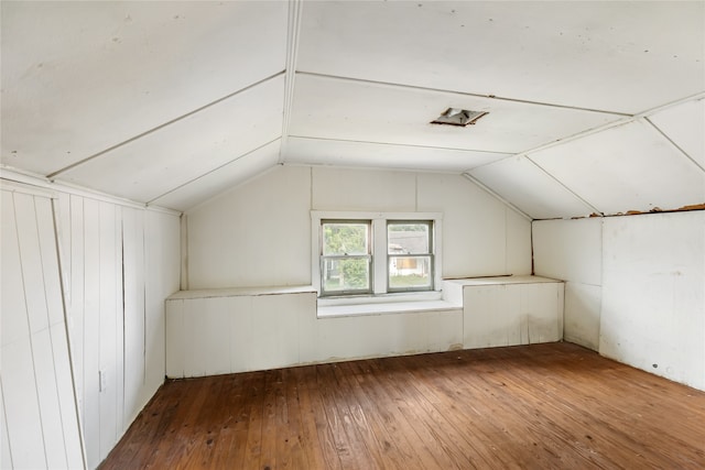 additional living space with vaulted ceiling, wood walls, and hardwood / wood-style flooring