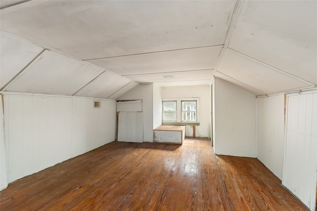 bonus room with wood-type flooring, wooden walls, and lofted ceiling