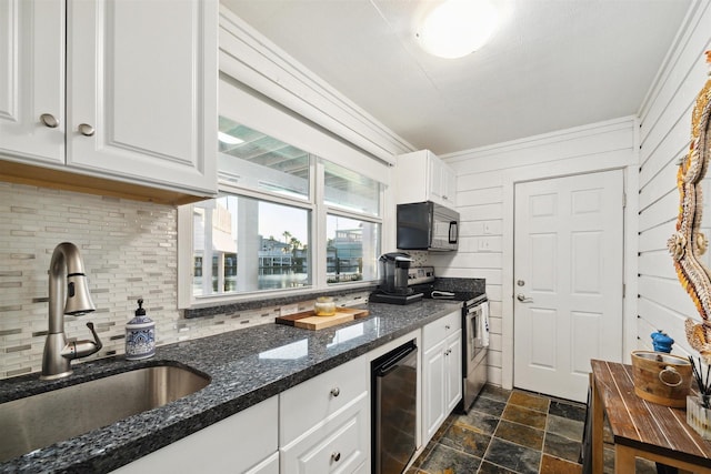 kitchen featuring sink, stainless steel range with electric stovetop, dark stone counters, beverage cooler, and white cabinets