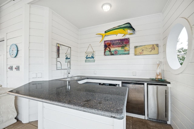 kitchen with white cabinetry, sink, dark stone countertops, and stainless steel refrigerator