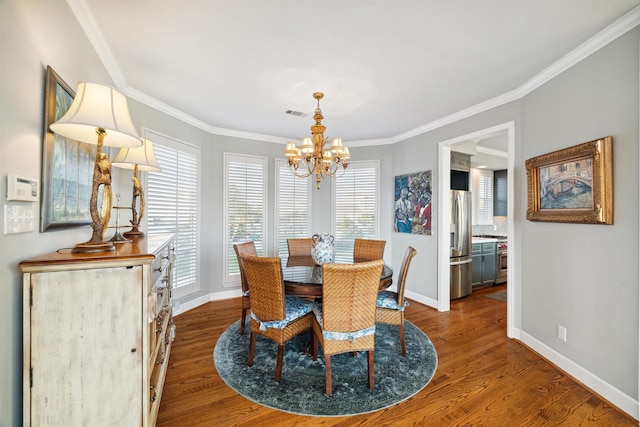 dining space featuring crown molding, a healthy amount of sunlight, hardwood / wood-style floors, and an inviting chandelier