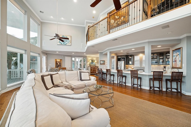 living room with hardwood / wood-style flooring, ornamental molding, and ceiling fan