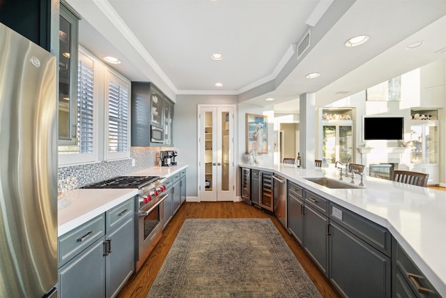 kitchen featuring sink, decorative backsplash, stainless steel appliances, crown molding, and dark wood-type flooring