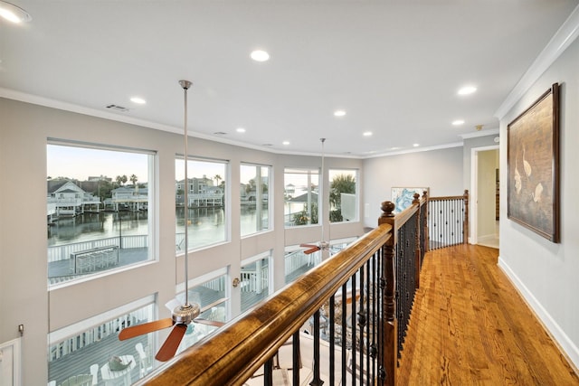 hallway featuring crown molding, hardwood / wood-style flooring, a wealth of natural light, and a water view