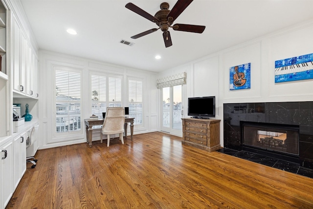 office with a tile fireplace, dark hardwood / wood-style floors, and ceiling fan