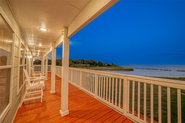 deck at dusk featuring a water view