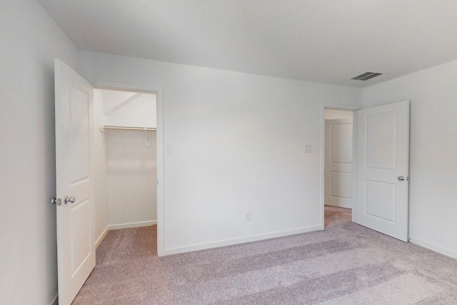 unfurnished bedroom featuring light carpet, a closet, and a walk in closet