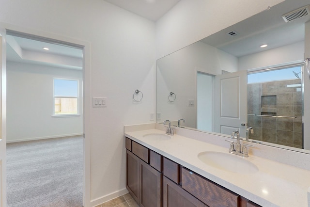 bathroom with a tile shower, tile patterned flooring, and vanity