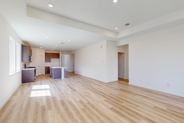 unfurnished living room featuring light wood-type flooring and sink