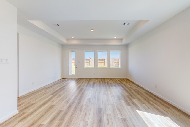 unfurnished room with a tray ceiling and light hardwood / wood-style flooring