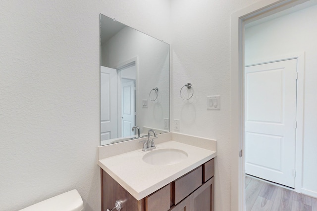 bathroom with hardwood / wood-style floors, vanity, and toilet