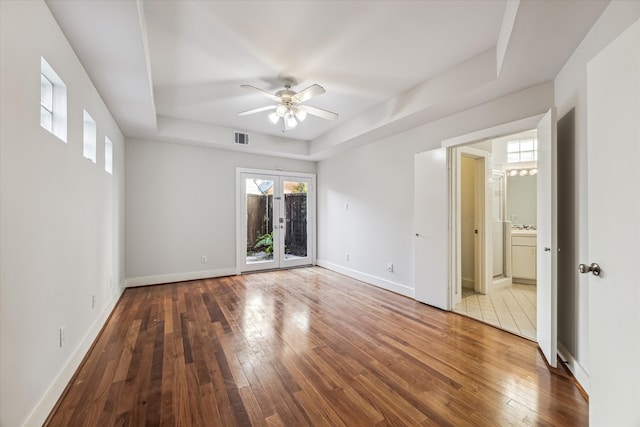 empty room with a tray ceiling, hardwood / wood-style floors, and ceiling fan